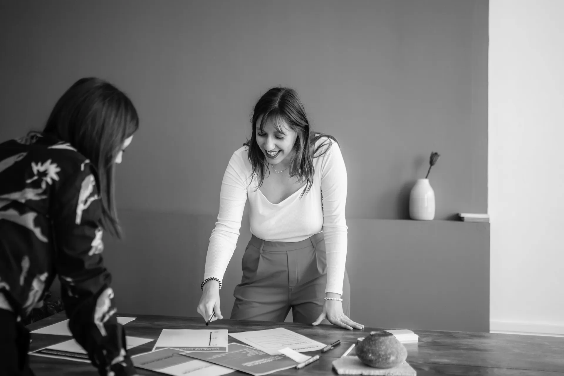 Mathilde Jadaud travaille avec une cliente autour d’une table couverte de documents